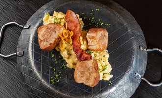 A delicious dish with tender meat, scrambled eggs, and crispy bacon, served on a stylish plate. The ingredients are garnished with fresh herbs. | © Hotel Alte Krone