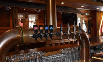 Eine gut strukturierte Bar mit mehreren Bierkranen und Gläsern. Die Holzverkleidung schafft eine gemütliche Atmosphäre. | © s‘Älpele | Marco Mitterer