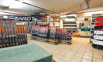 A ski rental shop with many skis and snowboards in a well-organized space. The walls are covered with equipment and accessories for winter sports. | © Aparthotel Kleinwalsertal Haller GmbH & Co KG